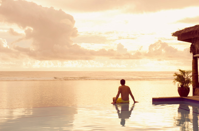 Travel Associates man sitting on infinity pool at dusk rarotonga