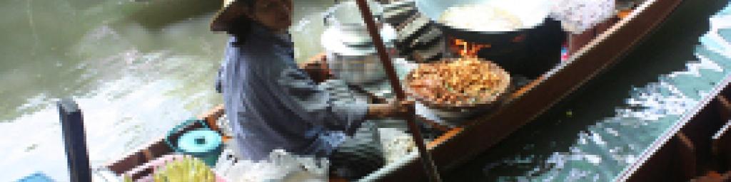 A vendor sells food from her boat in Thonburi, Bangkok