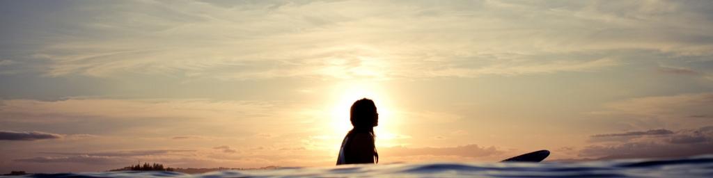 Silhouetted woman on longboard.