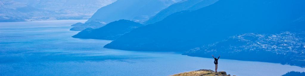 man standing on mountain above queenstown dusk