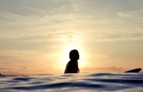 Silhouetted woman on longboard.