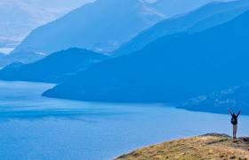 man standing on mountain above queenstown dusk